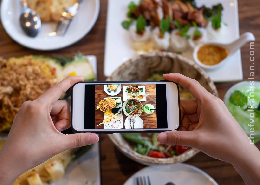 A diner photographing food on a restaurant table with a phone